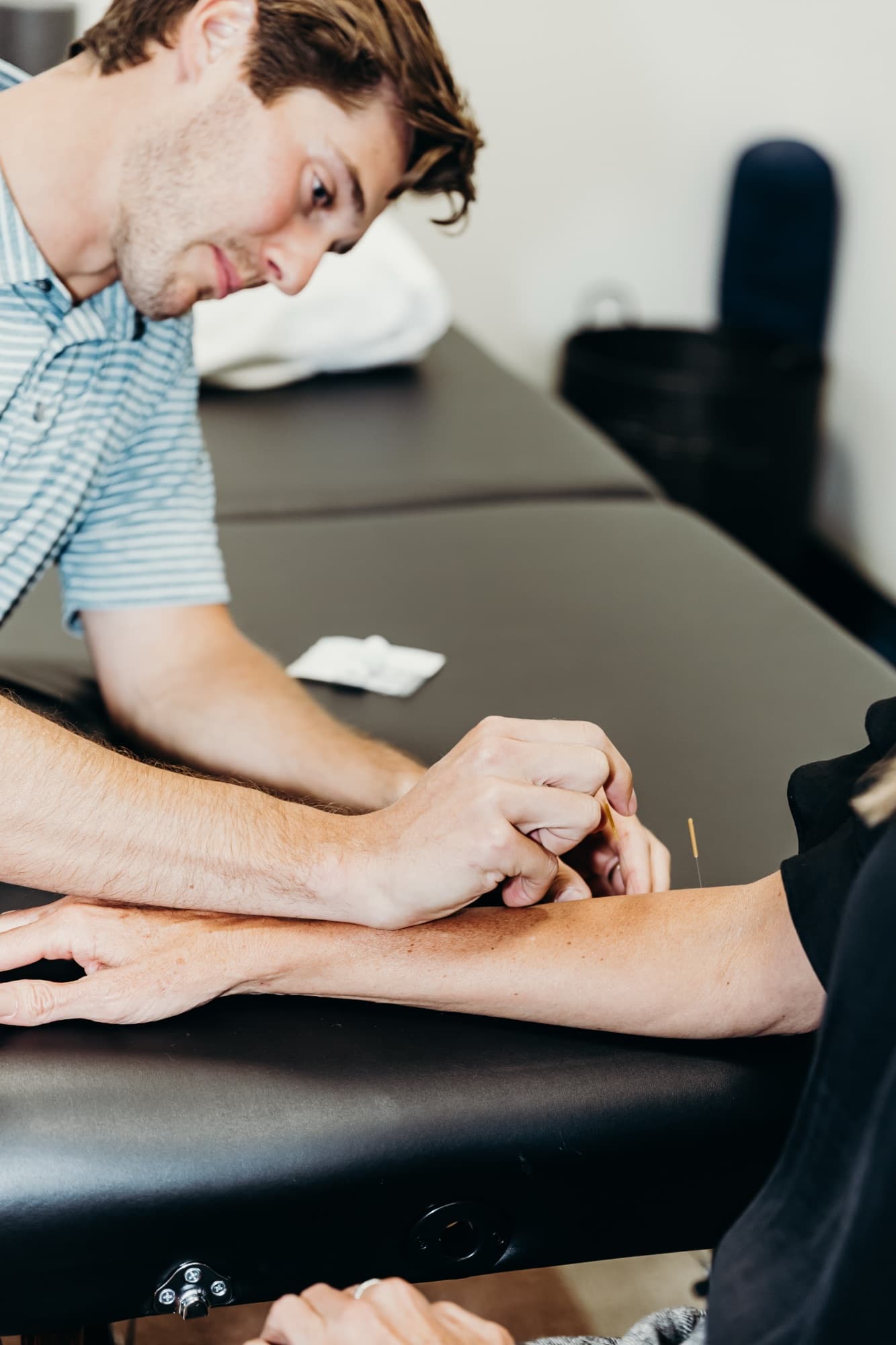 Close-up of dry needling being performed on a patient's forearm.