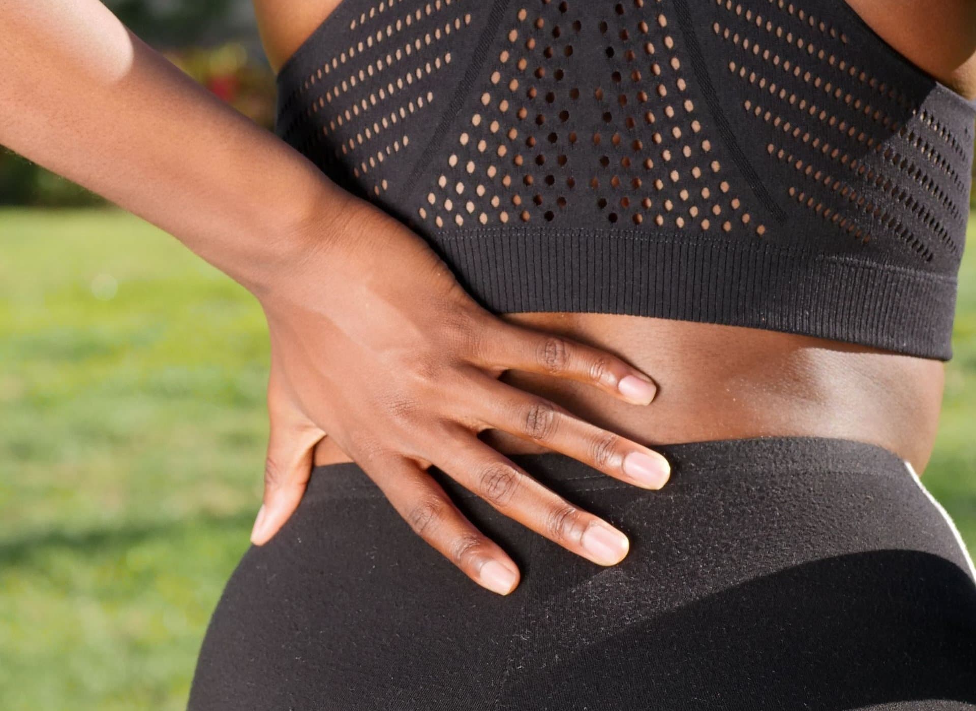 Active adult pressing a hand into a painful hip and lower back after exercise.