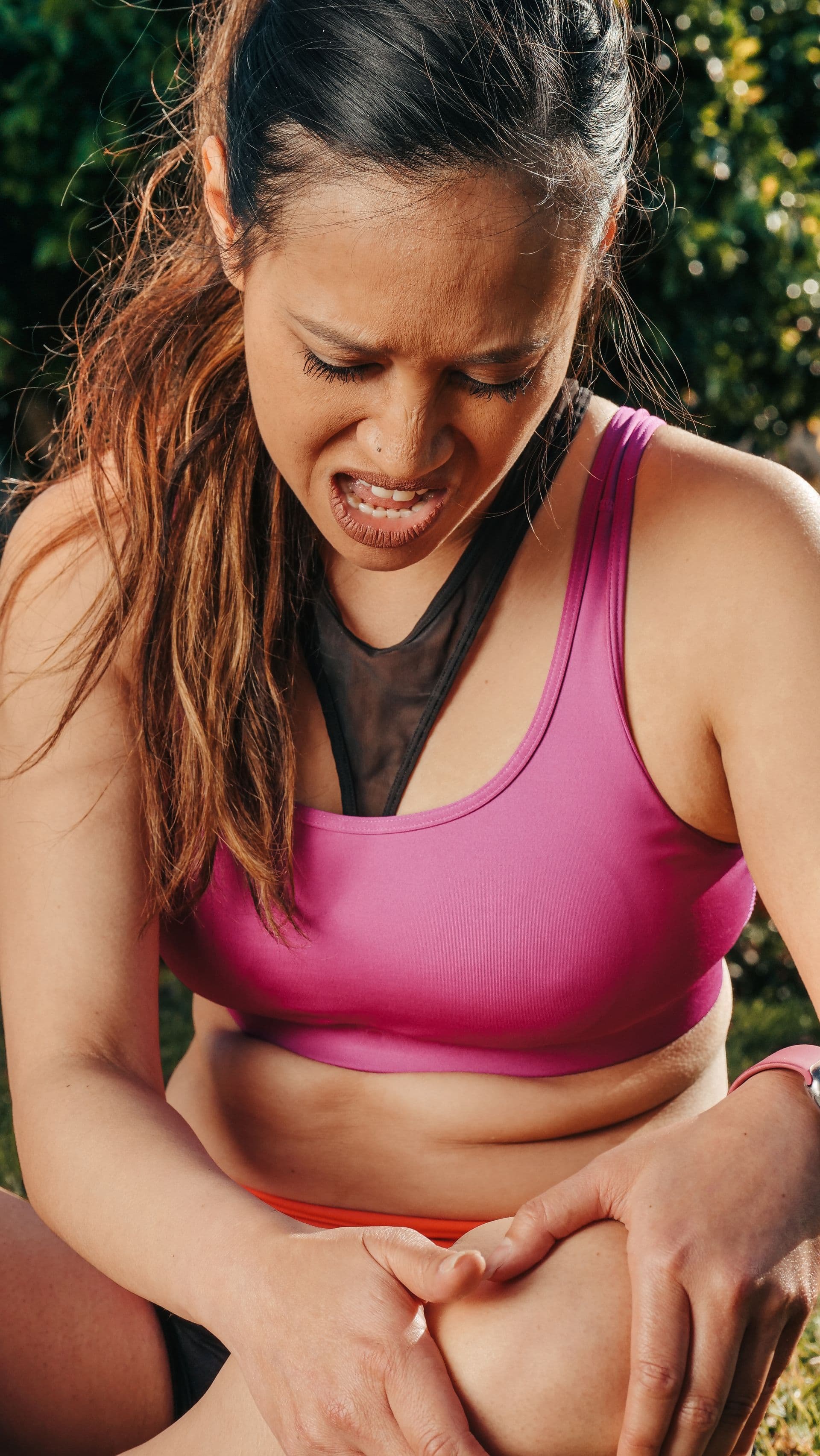 Runner gripping a painful knee during an outdoor workout.