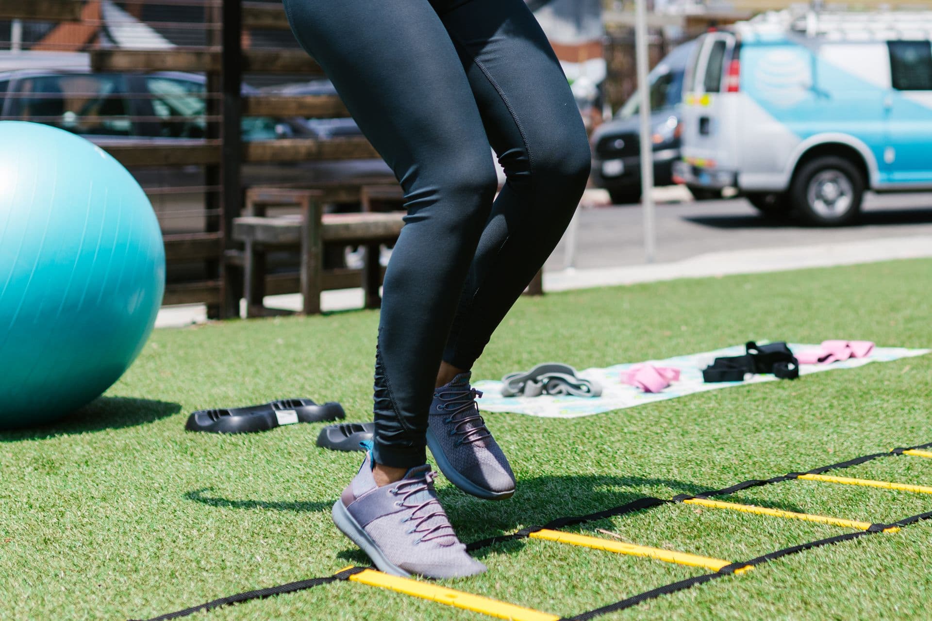 Athlete doing an agility-ladder footwork drill, the kind of movement retraining that rebuilds faulty patterns.