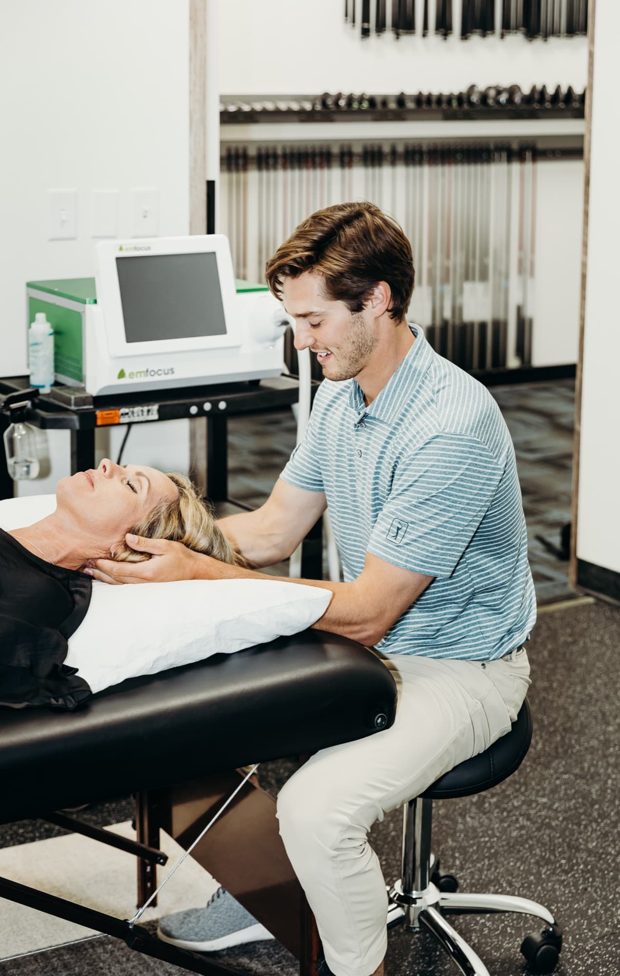 Dr. Taylor Wolf performing hands-on neck treatment for a patient lying on a table at Elevated Sport and Spine.