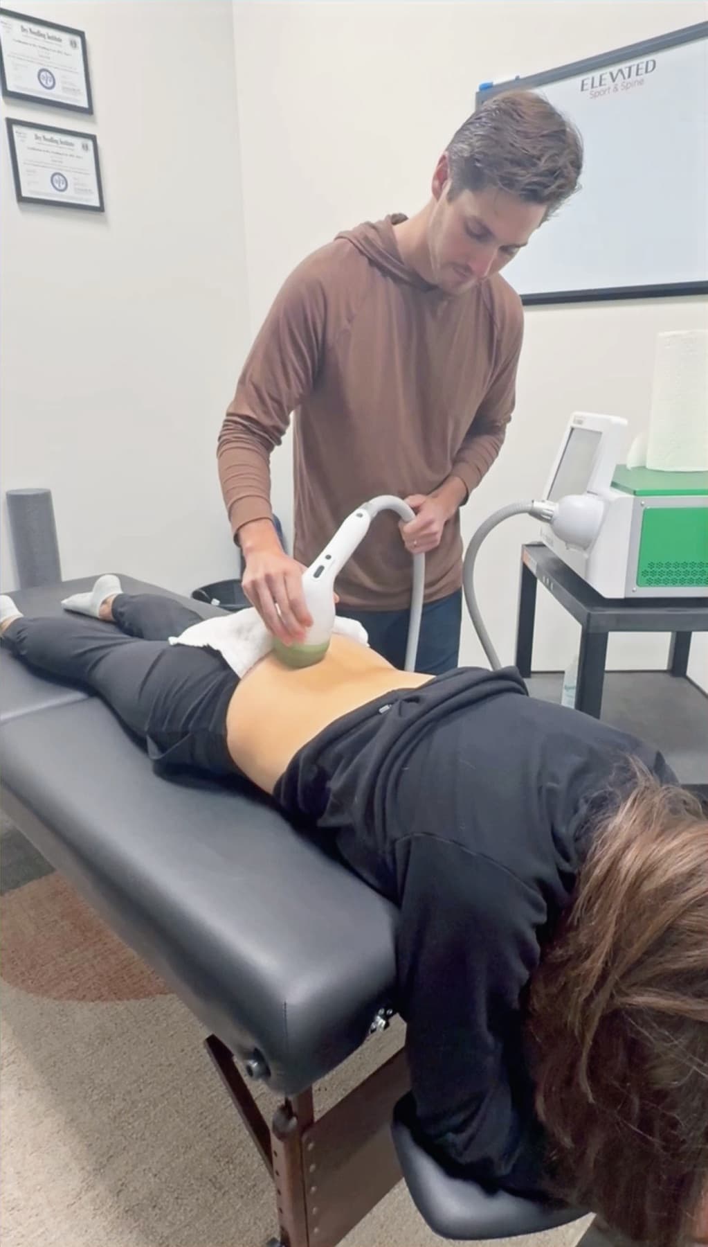 Shockwave therapy treatment applied to a patient's lower back at Elevated Sport and Spine.